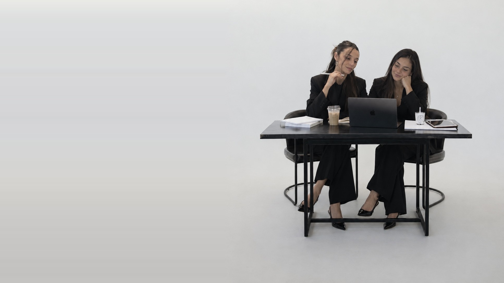 Luna y Catalina trabajando juntas frente a una laptop en un escritorio negro
