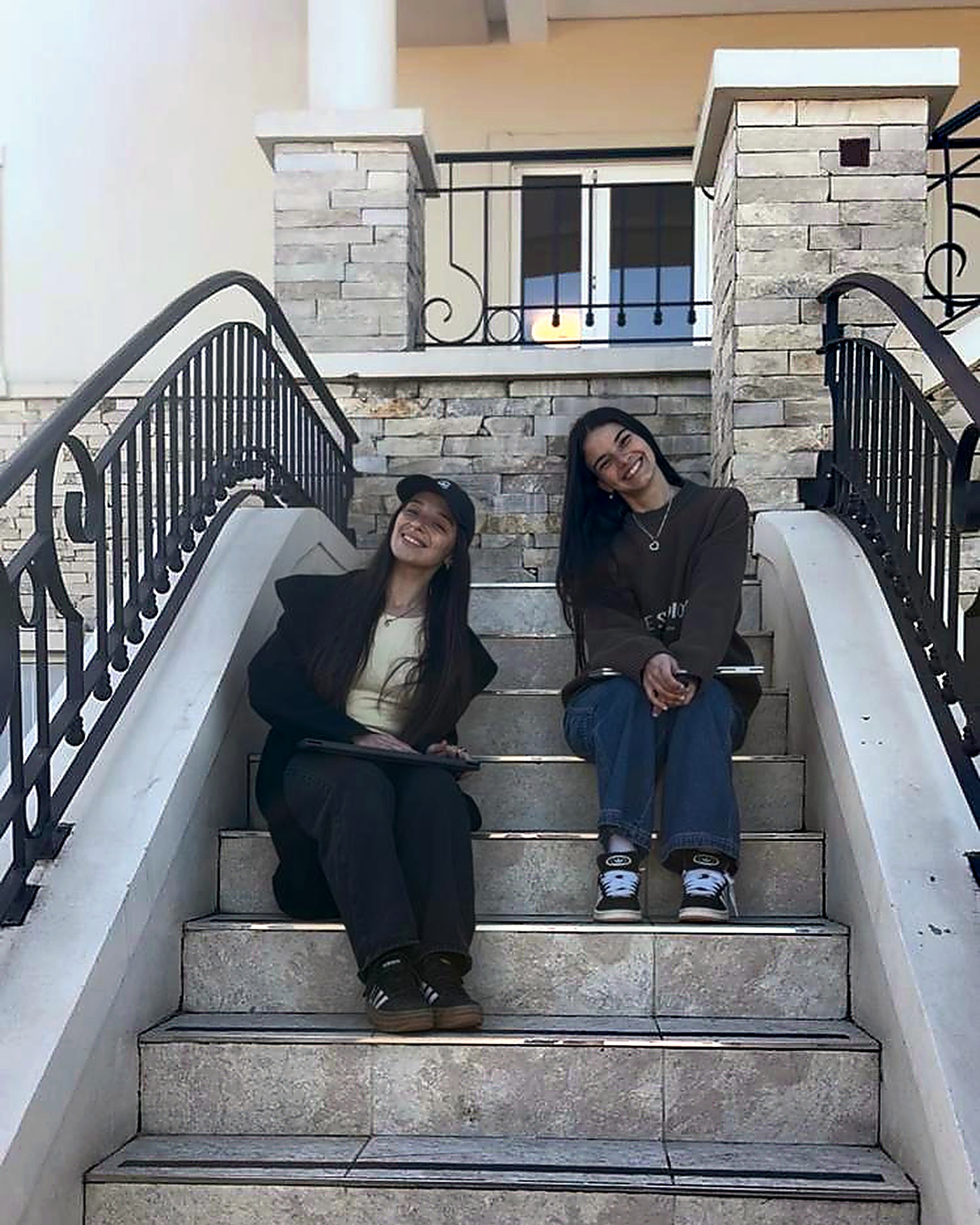 Luna y Cata, fundadoras de IMANTA, sentadas en una escalera de piedra